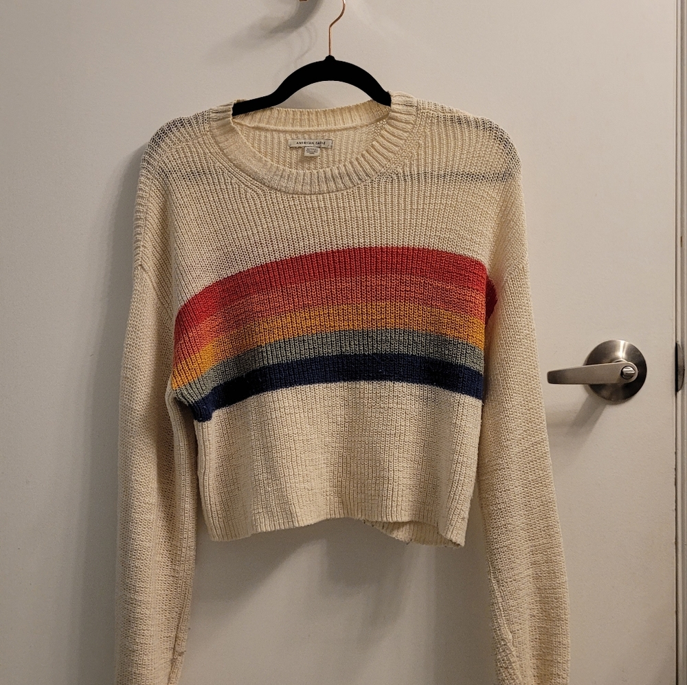 Cream-coloured sweater with multi-coloured stripes.